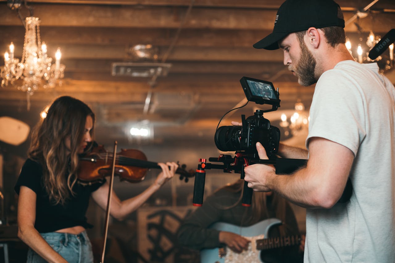 A filmmaker capturing a violinist on set, highlighting video production.