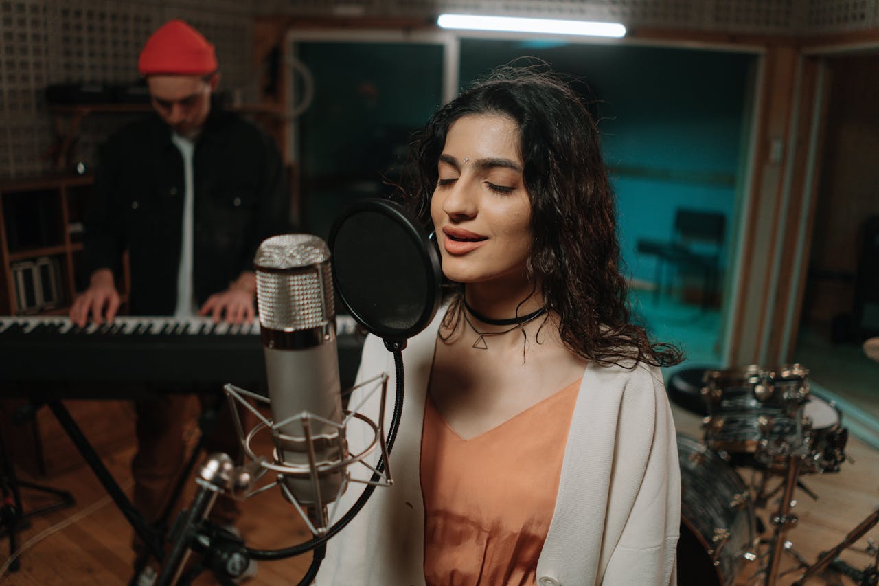 Two musicians rehearsing in a studio with a microphone and keyboard.